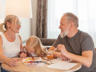 Grandparents and a child bond over painting at a cozy home setting, smiling and focused.
